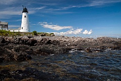 Wood Island lighthouse guards rocky shoreline.